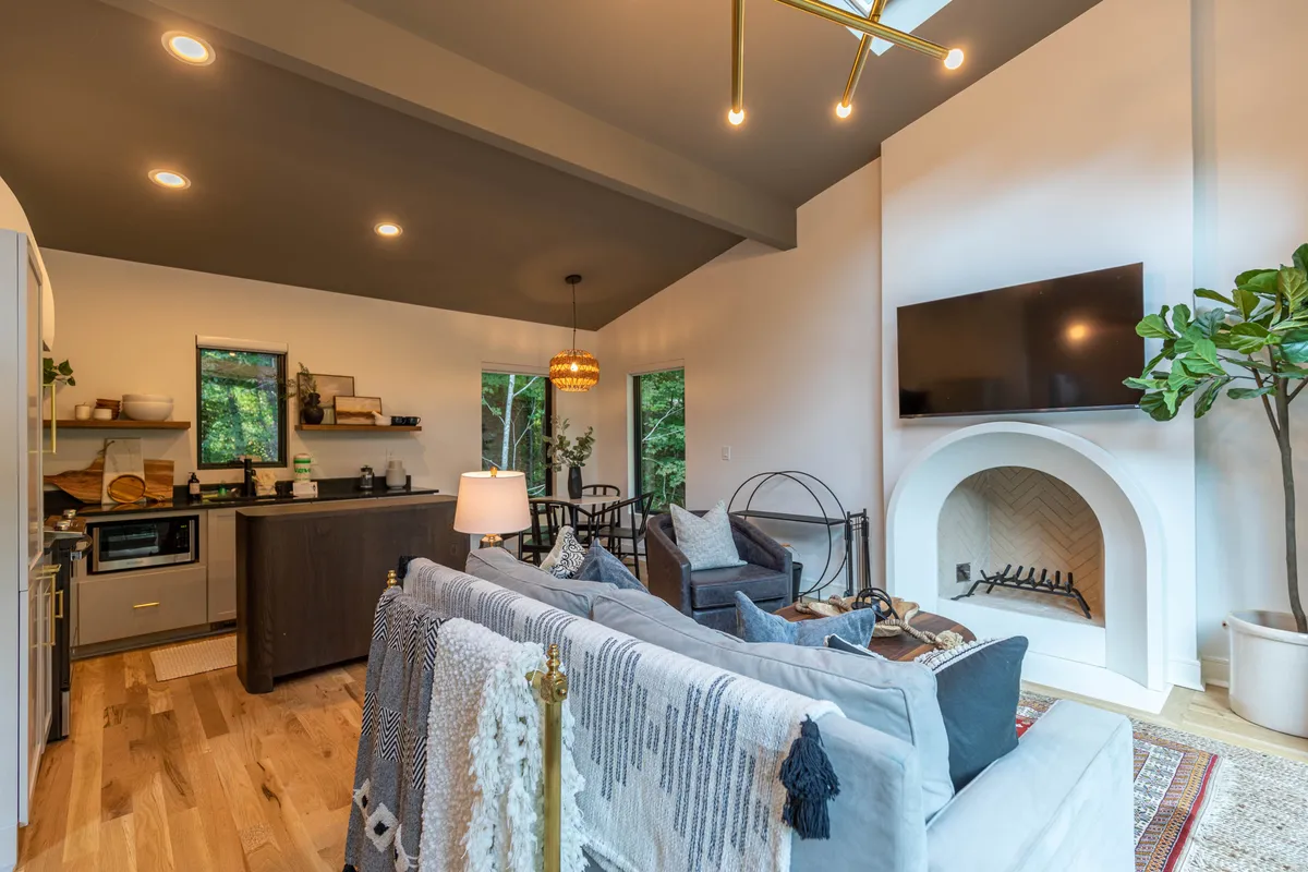 A wide view that links the kitchen counter to the living area, featuring a decorative sofa, a dining area, and a fireplace. The kitchen is equipped and seamlessly flows into spaces for entertaining, making it ideal for both family feasts and intimate meals.